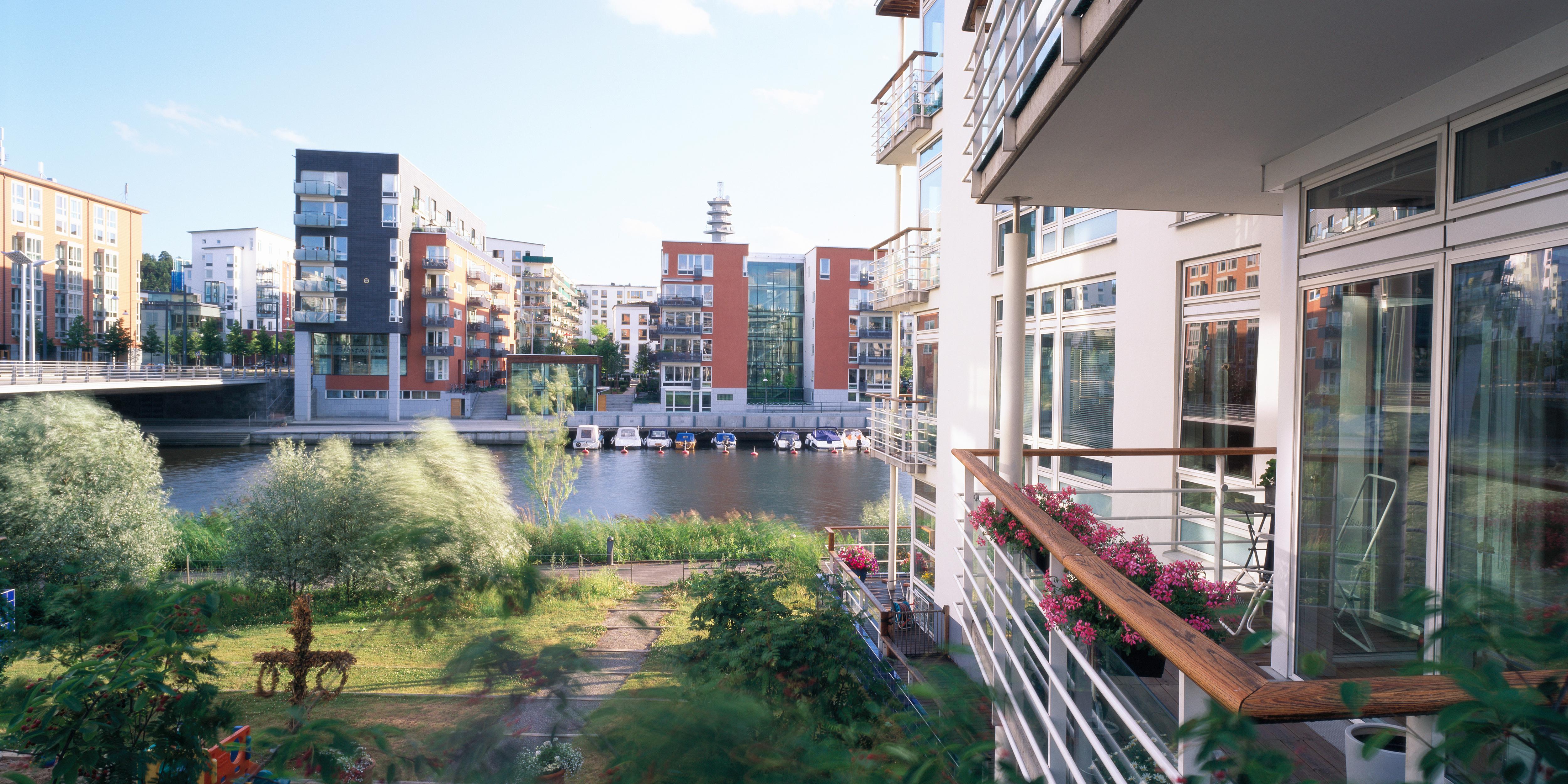Byggnader vid en hamn med småbåtar och lägenhetshus.