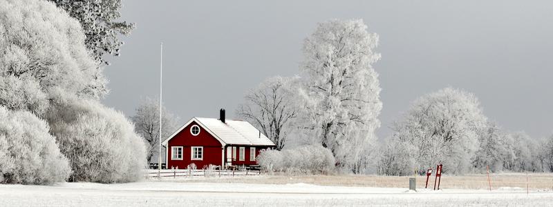 En röd stuga i vinterlandskap.